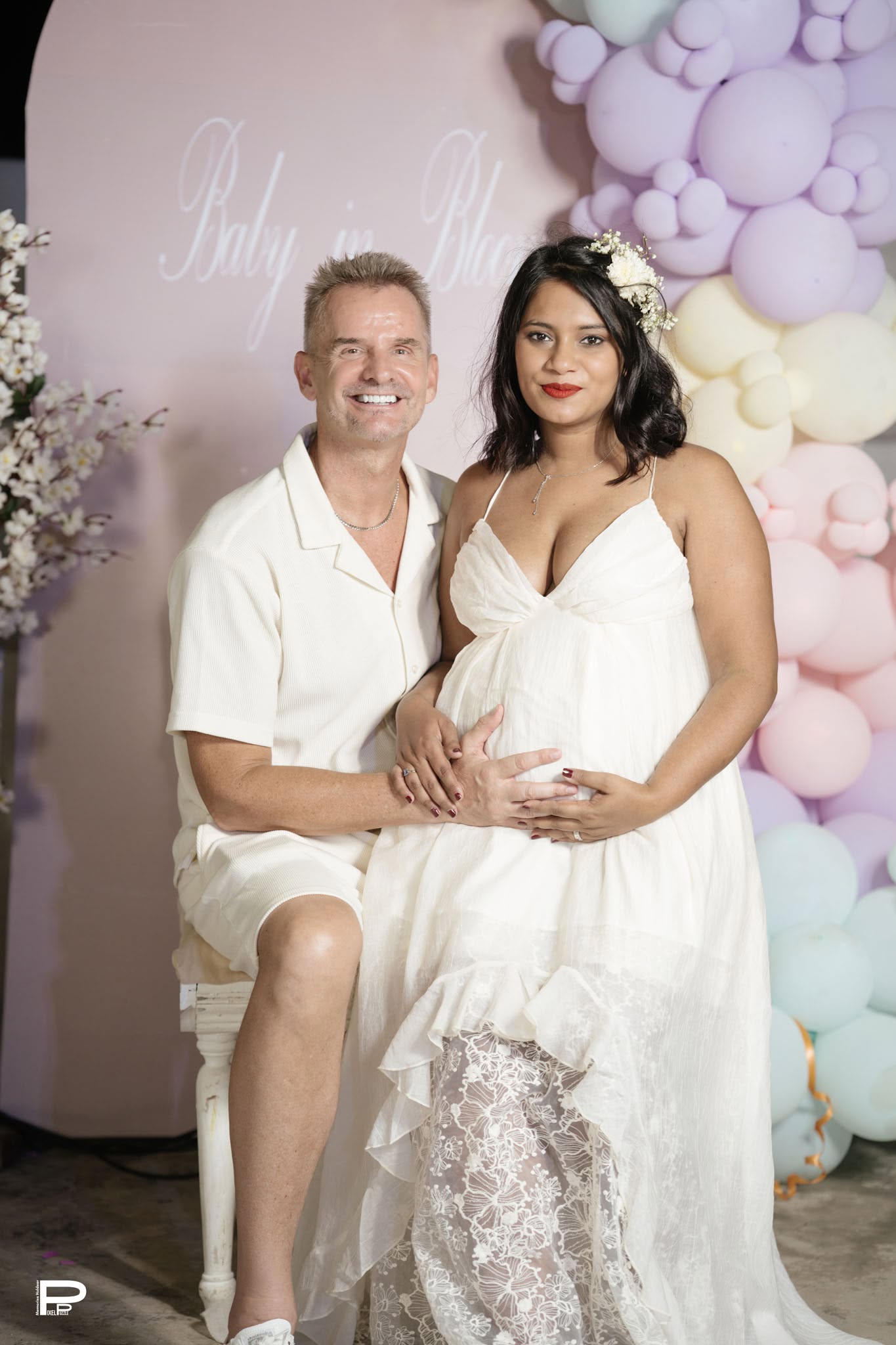 Expecting couple posing at a pastel baby shower setup