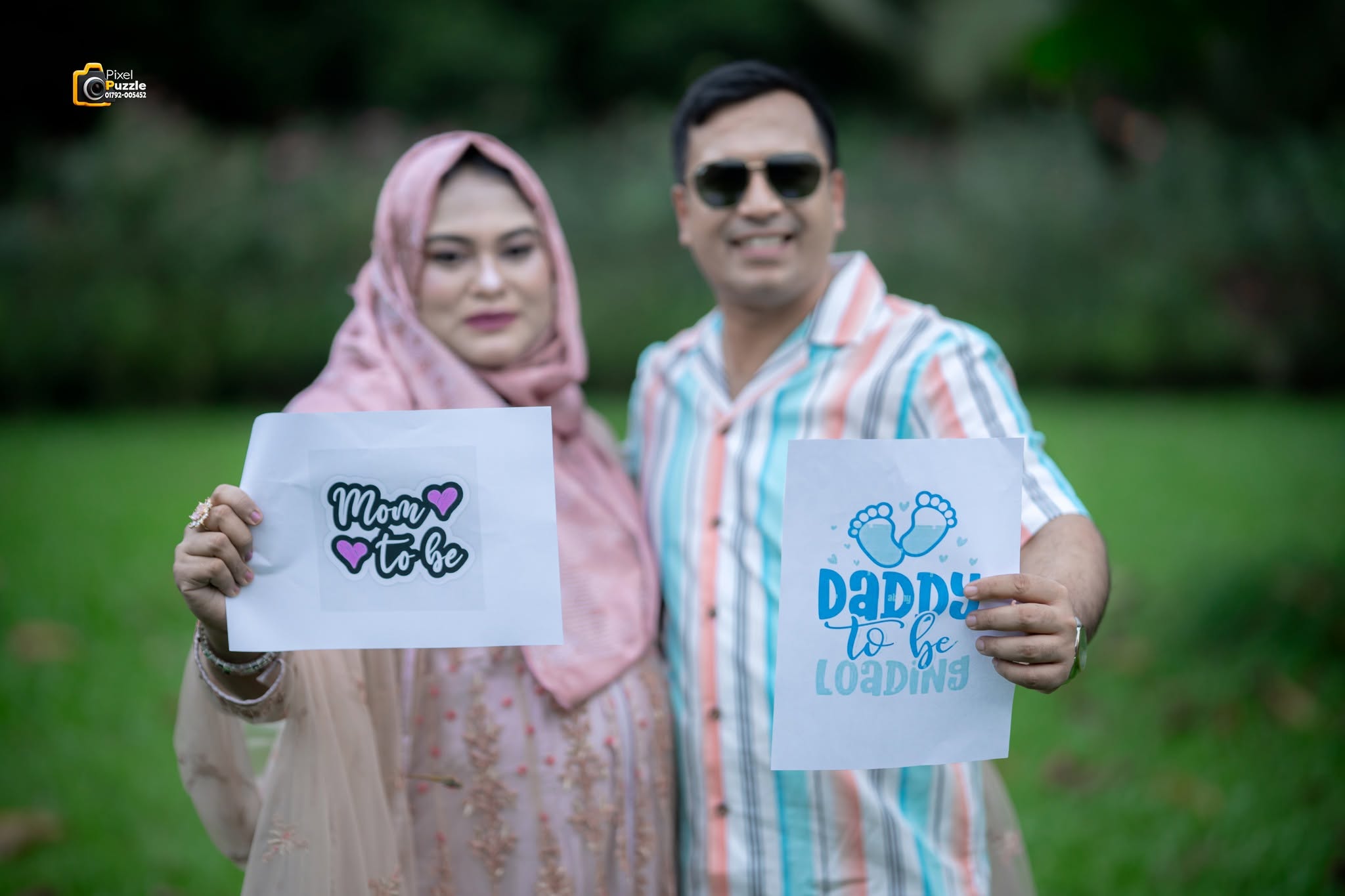 Parents-to-be holding baby announcement signs outdoors